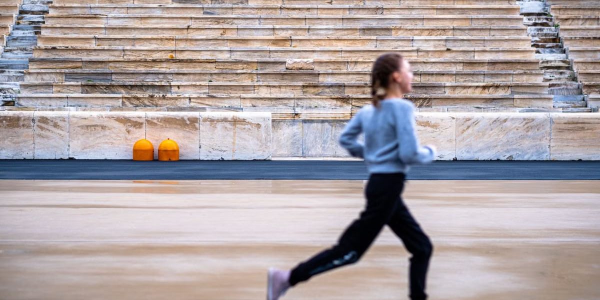 A girl runs in a historic stadium with empty stands, symbolizing youthful energy and ancient architecture.