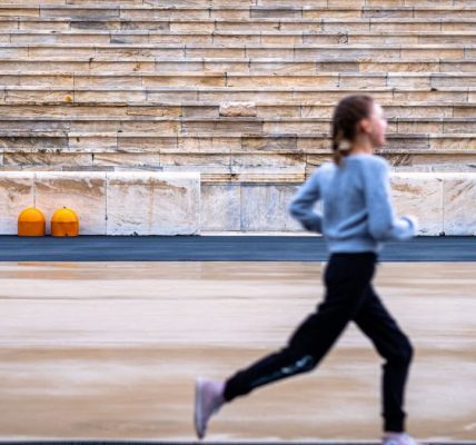 A girl runs in a historic stadium with empty stands, symbolizing youthful energy and ancient architecture.